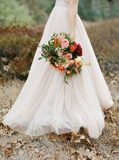 a woman in a white dress holding a bouquet of flowers and wearing a wedding dress