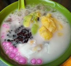 a green bowl filled with fruit and milk