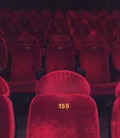 rows of red velvet seats with numbers on them in an auditorium or theater setting, facing the front row