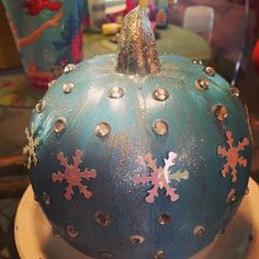 a blue pumpkin decorated with snowflakes and studs on it's side