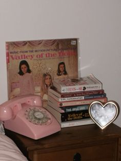 a pink telephone sitting on top of a wooden table next to a stack of books