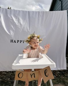 a baby sitting in a high chair with a happy one sign