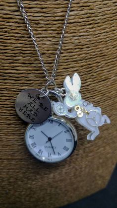 "Alice in Wonderland inspired pocket watch necklace, with resin steampunk-style White Rabbit and hand stamped quote pendant \"I'm late! I'm late! For a very important date! No time to say hello, goodbye! I'm late! I'm late! I'm late!\" Long-chain necklace with a perfectly functioning pocket watch, a stamped silver metal pendant which reads \"We're All Mad Here\" and a resin handmade pendant, featuring real steampunk clock gears, in the shape of the White Rabbit silhouette. The watch works on bat Rabbit Silhouette, Clock Gears, Alice In Wonderland Inspired, Hello Goodbye, Steampunk Clock, Pocket Watch Necklace, Steampunk Style, Face Reveal, Long Chain Necklace