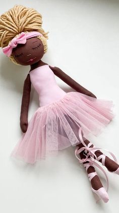 a doll with blonde hair wearing a pink tutu and ballet shoes on the floor