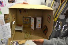 a woman holding up a cardboard doll house