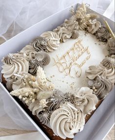 a birthday cake with white frosting and brown icing in a box on a table