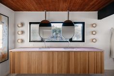 a bathroom with two round mirrors above the sink and wooden countertop, along with hanging lights