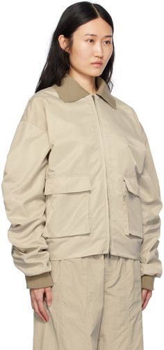 Nylon twill bomber jacket. · Rib knit spread collar, back hem, and cuffs · Two-way zip closure · Bellows pockets · Ruching at sleeves · Welt pocket at interior · Full satin lining · Logo-engraved silver-tone hardware Supplier color: Oak Beige Windbreaker For Work With Pockets, Beige Workwear Windbreaker With Pockets, Workwear Beige Windbreaker With Pockets, Beige Outerwear With Flap Pockets For Streetwear, Winter Workwear Track Jacket With Side Pockets, Fall Nylon Track Jacket With Zip Cuffs, Collared Track Jacket With Pockets For Fall, Fall Track Jacket With Pockets And Collared Shape, Collared Windbreaker With Pockets For Streetwear