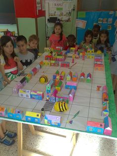 a group of children sitting around a table playing with blocks and magnets on it