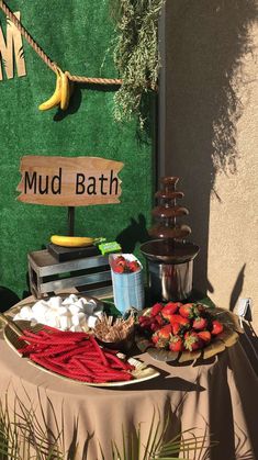 a table topped with lots of food next to a sign that says mudbath