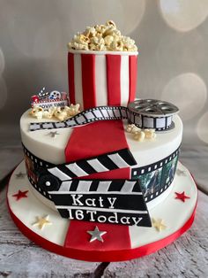 a birthday cake decorated with popcorn, film reels and stars on the bottom tier