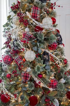 a christmas tree decorated with red and white plaid balls, greenery, ornaments and ribbons