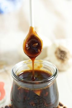 a jar filled with liquid sitting on top of a wooden table next to coffee beans