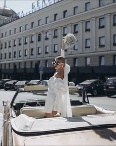 a woman in white is standing on top of a car with a pom - pom