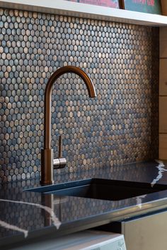 a kitchen sink with a faucet in front of a tiled backsplash