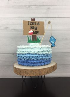 a blue and white cake sitting on top of a wooden table next to a sign that says i am'm big one