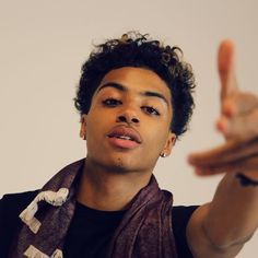 a young man is making the peace sign with his fingers while wearing a scarf around his neck