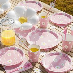 a table set with pink and white plates, cups, utensils and flowers