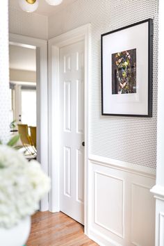 the interior of a home with white walls and wood floors, framed artwork on the wall