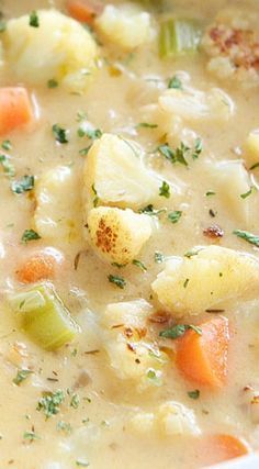 a close up of a bowl of soup with carrots, cauliflower and celery