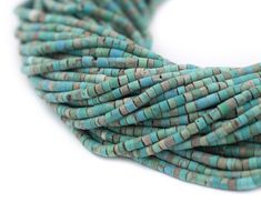 turquoise and brown beads are stacked together on a white surface