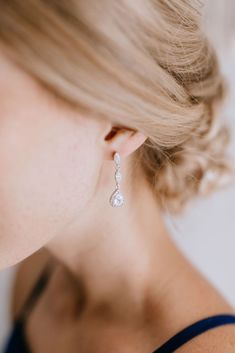 a woman with blonde hair wearing a pair of white diamond earrings on her left ear