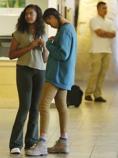 two women standing next to each other looking at their cell phones