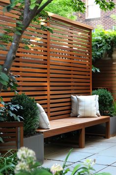 a wooden bench sitting under a tree next to a planter filled with flowers and greenery