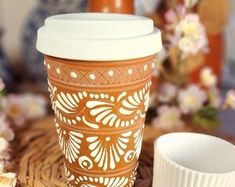 a coffee cup sitting on top of a wooden table next to a white paper cup