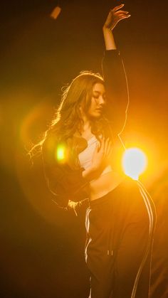 a woman standing on top of a stage with her arms in the air and lights behind her