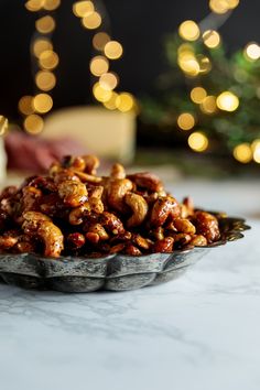 a bowl filled with nuts sitting on top of a table next to a christmas tree