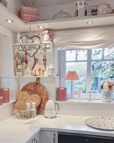 a kitchen with white cabinets and lots of stuff on the shelf above the stove top