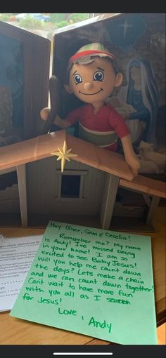 a doll house with a note written on it and an elf figurine next to it