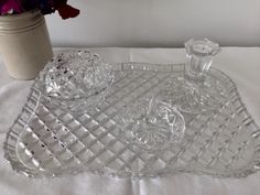 a clear glass tray with an ornate design on it next to a vase and flowers