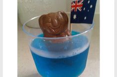 a glass filled with blue liquid and a chocolate elephant sticking out of it's mouth