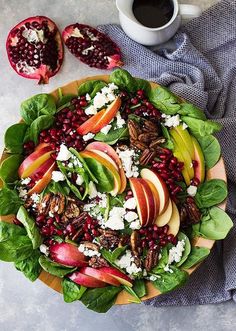 a salad with spinach, apples, pecans and feta cheese on top