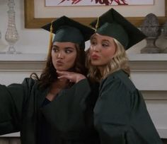 two women in graduation caps and gowns posing for the camera