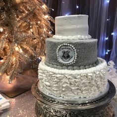 a three tiered cake sitting on top of a table next to a christmas tree