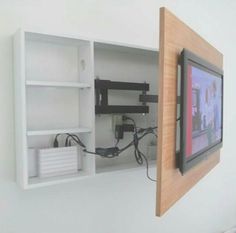 a tv mounted to the side of a white wall next to a wooden framed object