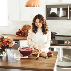 a woman standing in a kitchen preparing food on top of a wooden counter next to an oven