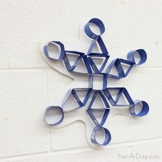 an origami snowflake made out of blue paper on a white wall