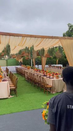 a man standing in front of a long table covered with yellow and orange cloths