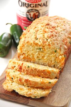 a loaf of bread sitting on top of a wooden cutting board next to green peppers