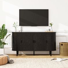 a flat screen tv sitting on top of a wooden cabinet next to a potted plant