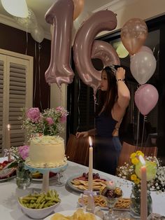 a woman standing in front of a table filled with food and balloons that say 50