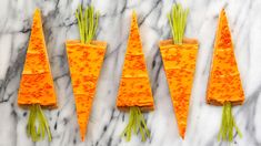 four carrots are arranged in the shape of pyramids on a marble countertop