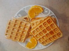 three waffles on a plate with orange slices