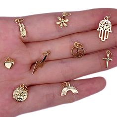 a person's hand is holding several different types of gold jewelry on their fingers