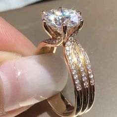 a close up of a person's hand holding a ring with a diamond on it