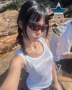 a woman sitting on top of a rock next to a glass filled with liquid in her hand